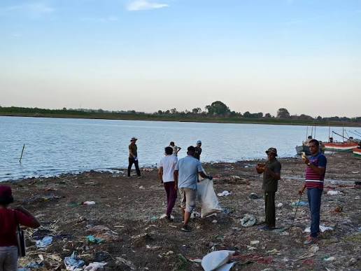 A water body's shoreline covered in plastic and other waste before a cleanup